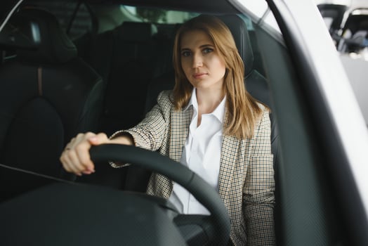 Photo of happy young woman sitting inside her new car. Concept for car rental.