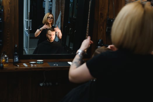 Woman barber cutting hair to a bearded man photo