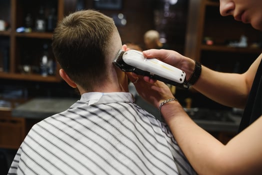 Young handsome barber making haircut of attractive bearded man in barbershop. photo