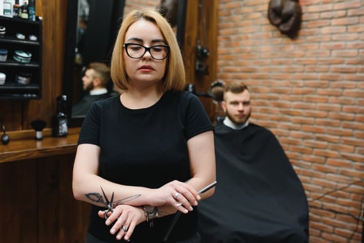 Portrait of fashion woman barber hairstylist with scissors in hand in the barbershop photo