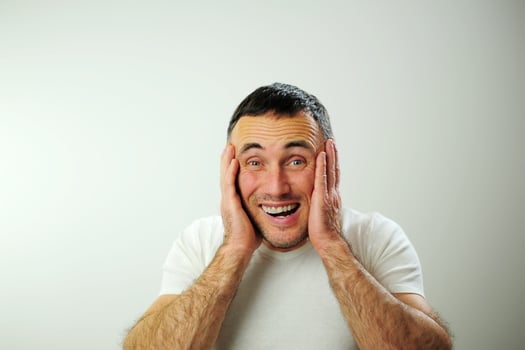 Win fun vacation travelDifferent cheerful positive emotions of an adult man with gray black hair Open funny cheerful blue eyes White t-shirt gray background wrinkle forehead stick out tongue photo