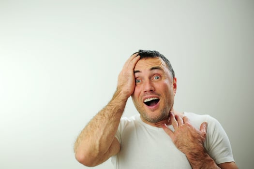 Adult unshaven handsome man Holding on to head with mouth open hairy arms blue eyes black hair Emotions surprise win billboard banner Open wide blue eyes white studio Advertising space for text photo