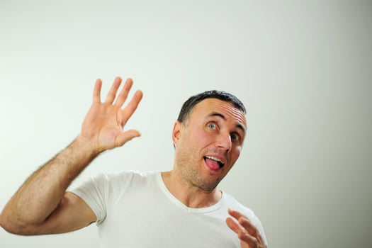 Win fun vacation travelDifferent cheerful positive emotions of an adult man with gray black hair Open funny cheerful blue eyes White t-shirt gray background wrinkle forehead stick out tongue photo