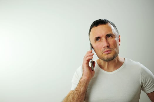 Adult strict man talking on the phone He is angry and a little dissatisfied with the conversation Studio all white phone t-shirt and iPhone space for text white background photo