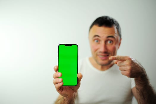 Positive millennial man showing huge brand new smartphone with empty screen and thumb up over white studio background, mockup, panorama with copy space, newest mobile app concept photo