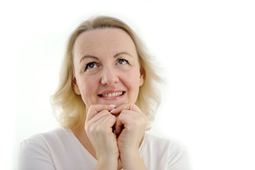beautiful middle-aged woman is waiting for gift for holiday she folded hands near face expectation tenderness beauty on white background place for text buy sale advertising excellent service photo