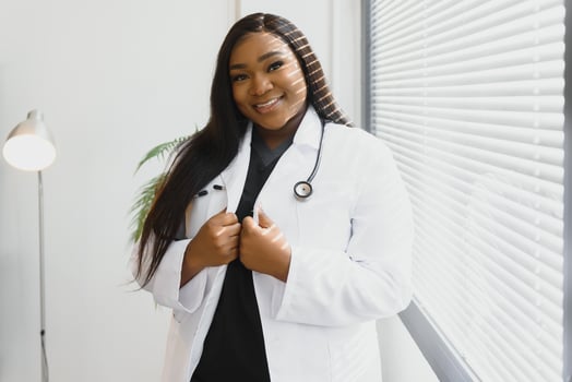 Portrait of beautiful smiling female african american doctor standing in medical office. Health care concept, medical insurance, copy space photo
