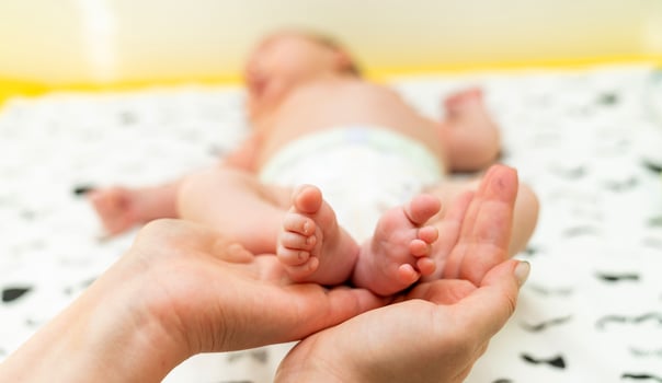 Newborn baby feet. Cute feet of sleeping baby. Mothers hands photo