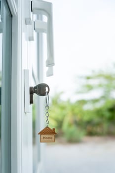Landlord key for unlocking house is plugged into the door. Second hand house for rent and sale. keychain is blowing in the wind. mortgage for new home, buy, sell, renovate, investment, owner, estate photo