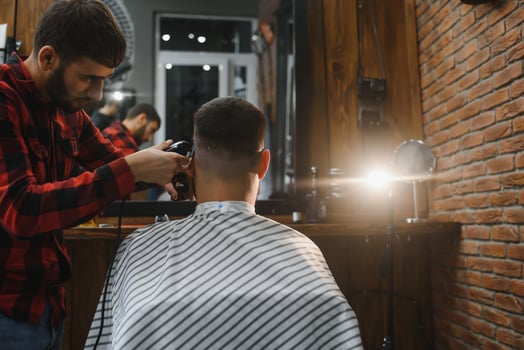 Barber shop. Man with wife in barber's chair, hairdresser Barbershop styling his hair. photo