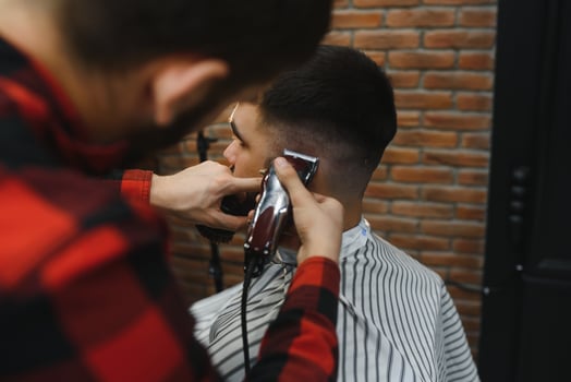 Serious Young Bearded Man Getting Haircut By Barber. Barbershop Theme. photo