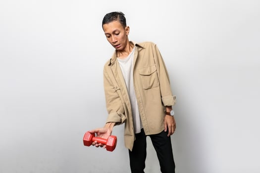 an asian man with a tan jacket is lifting dumbbells for muscle training or fitness photo