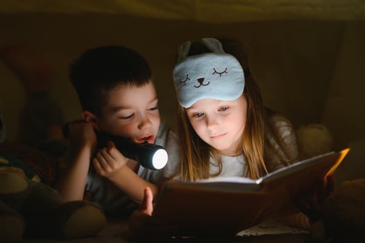 happy family children reading a book with a flashlight in a tent at home photo