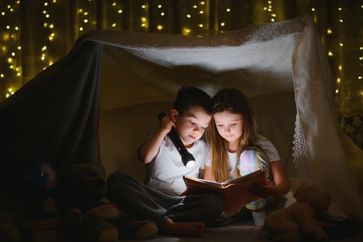 reading and family games in children's tent. boy and girl with book and flashlight before going to bed photo