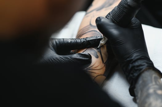 tattooist with his machine tattooing on the arm with the design drawn, concept of art and design photo