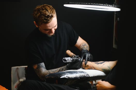 tattooist with his machine tattooing on the arm with the design drawn, concept of art and design photo