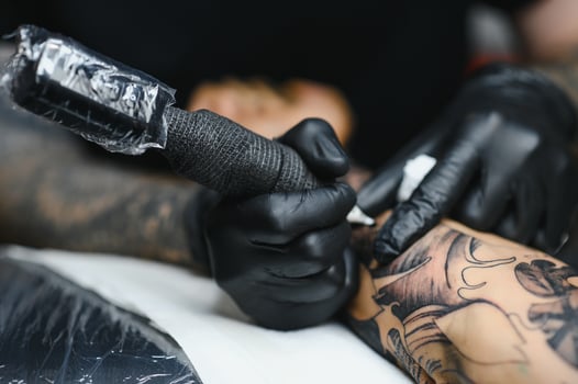 Tattoo salon. The tattoo master is tattooing a man. Tattoo machine, safety and hygiene at work. Close-up, tinted, tattooist. photo