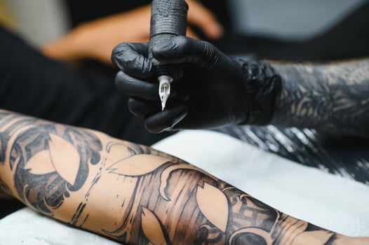 Tattoo salon. The tattoo master is tattooing a man. Tattoo machine, safety and hygiene at work. Close-up, tinted, tattooist. photo