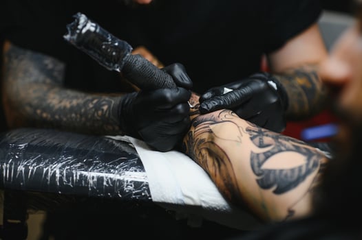 Tattoo salon. The tattoo master is tattooing a man. Tattoo machine, safety and hygiene at work. Close-up, tinted, tattooist. photo