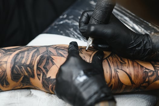 Tattoo salon. The tattoo master is tattooing a man. Tattoo machine, safety and hygiene at work. Close-up, tinted, tattooist. photo