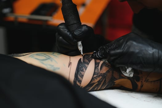 Close up of the tattoo machine. Tattooing. Man creating a picture on his back by a professional tattoo artist. photo