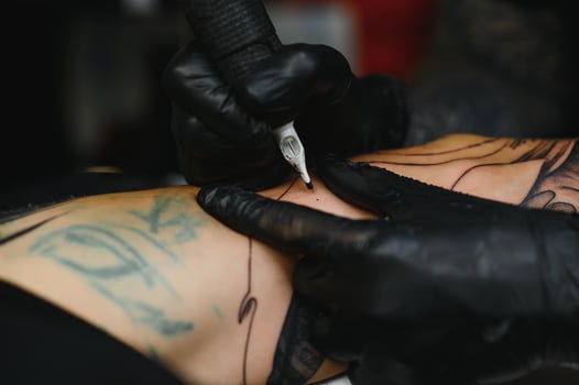 Tattoo salon. The tattoo master is tattooing a man. Tattoo machine, safety and hygiene at work. Close-up, tinted, tattooist. photo