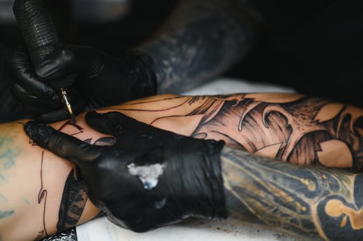 Tattoo salon. The tattoo master is tattooing a man. Tattoo machine, safety and hygiene at work. Close-up, tinted, tattooist. photo