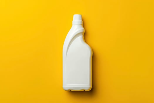 A white plastic bottle of cleaning solution on a yellow background photo