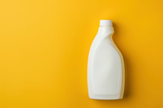 A white plastic bottle of liquid is on a yellow background photo