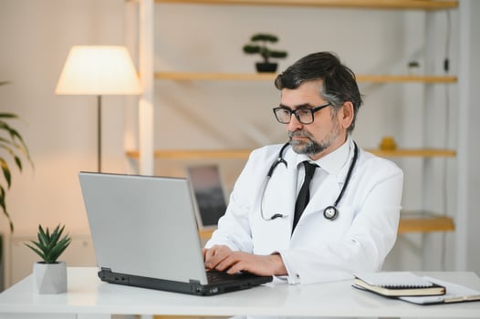 Portrait of a serious doctor using laptop in medical office photo