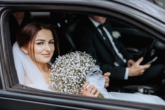 A bride and groom are in a car photo