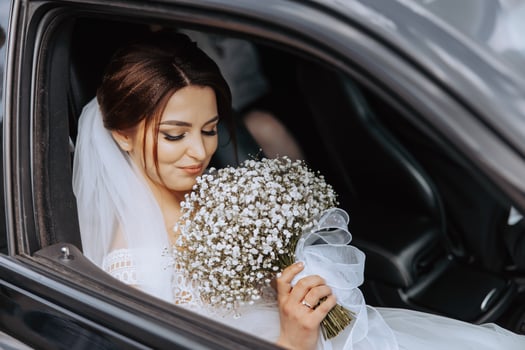 A bride is driving in a car with a bouquet of white flowers photo