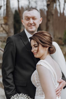 The bride and groom are walking in nature on their wedding day. A man hugs a woman. Zhidka leans tightly against her husband photo