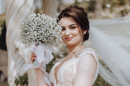 A woman is holding a bouquet of white flowers and wearing a white wedding dress photo