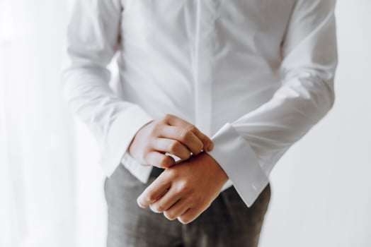 A man in a white shirt is adjusting his shirt sleeves photo