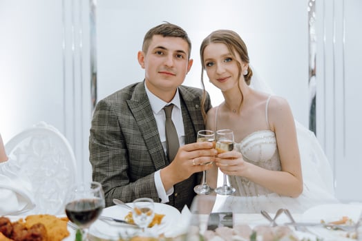 A man and woman are posing for a picture with wine glasses in front of a table w photo