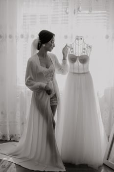 A woman stands in front of a wedding dress and a mannequin photo