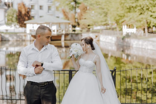 A man and a woman are standing by a pond, the man is wearing a watch photo