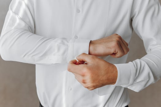 A man is getting dressed in a white shirt photo