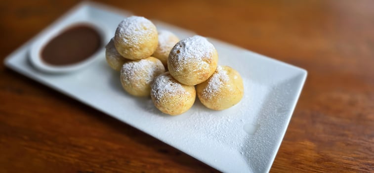 Homemade Dutch poffertjes mini pancakes with icing powdered sugar and chocolate fillings with additional chocolate sauce photo