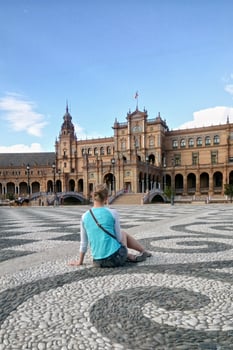 Back view of solo traveler girl sitting on the square of Spain in Seville. Backview of woman tourist in Sevilla trip. Solo vacation concept. photo