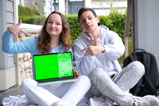 people, education, technology and school concept happy students with laptop computer chromakey laptop sit on porch point finger teen boy teen girl photo