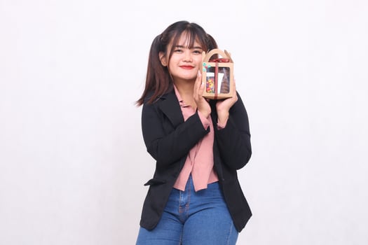 Beautiful Asian girl in her 20s smiling spoiled enthusiastically lifting Christmas gifts in the form of hampers looking at the camera on a white background for advertising materials,banners,billboards photo