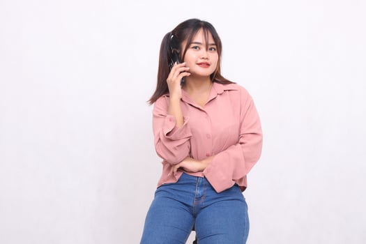 Beautiful happy asian woman in her 20s wearing casual shirt with arms crossed using mobile phone pose looking at camera on white background during studio portrait for banner ad, banner, billboard photo