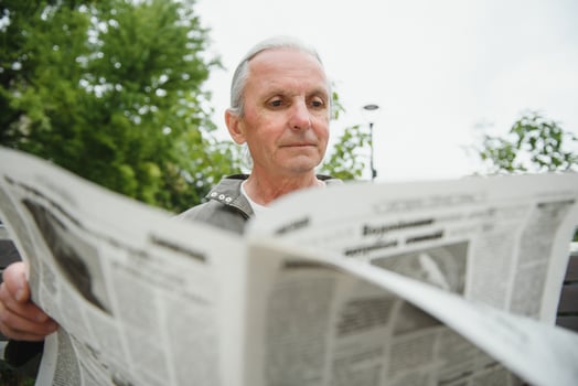 Portrait of senior man reading on bench during summer day. photo