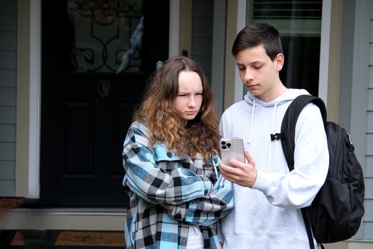 boy shows something on laptop of girl she corrects mistakes she smiles a briefcase loser first relationship boy teenager clothes autumn spring near the house at door to come to friend to help photo