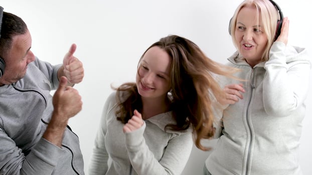 good positive-psychological relations in the family approval teenage girl dancing on a white background in headphones the girl shows the movement of the parents raise their thumbs up they like photo