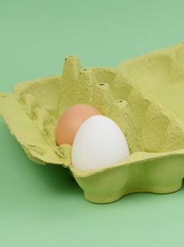 Two chicken eggs in a paper box on a green background photo