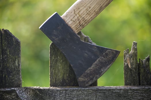 Detailed view of axe lodged into an old, weathered wooden fence photo