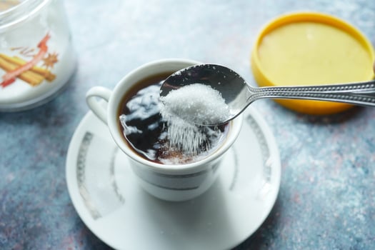 pouring white sugar in a coffee cup , photo